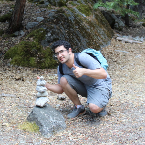 Stephen at Yosemite kneeling with thumbs-up next to his rock tower